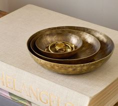 three brass bowls sitting on top of a book with the word, helancingo written in gold