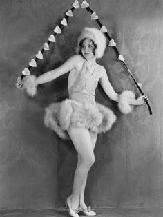 an old black and white photo of a woman wearing a costume with pom poms