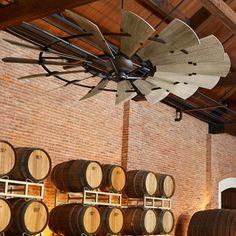 wine barrels are lined up in a cellar with an old fan hanging from the ceiling