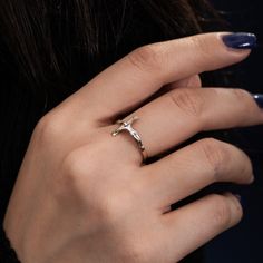 a woman's hand wearing a ring with a cross on it