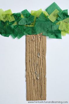 a paper tree made out of wood sticks with green leaves on the top and bottom