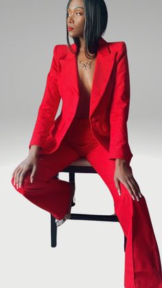 a woman in a red suit sitting on a chair