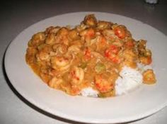 a white plate topped with rice covered in sauce and shrimp next to broccoli