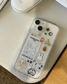 an iphone case with stickers on it sitting next to a keyboard and mouse,