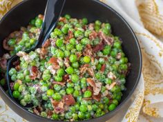 a bowl filled with peas and bacon on top of a table