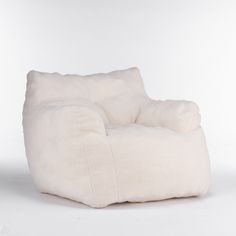 a white chair that is made out of sheepskin and has a pillow on it