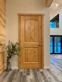 a wooden door in a white room with wood paneling on the walls and floor