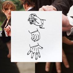 two people holding up a paper with drawings on it and one person pointing at something