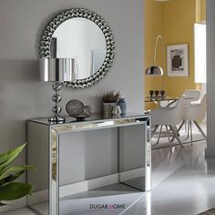 a living room with a table and mirror on the wall next to a potted plant