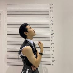 a man standing in front of a mugshot wall with his hand on his chest