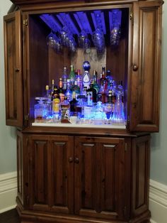 a wooden cabinet filled with lots of bottles and glasses on top of it's sides