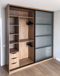 an open closet with wooden shelves and glass doors