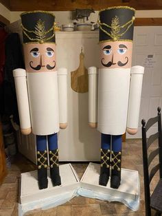 two wooden nutcrackers are standing next to each other in front of a refrigerator