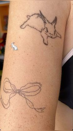 a woman's arm with tattoos on it and an image of a rabbit in the background