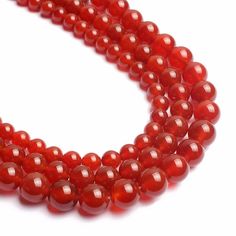 red agate beads are arranged on a white surface, with one bead in the middle