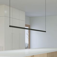 an empty kitchen with white cabinets and black lights hanging from the ceiling over the counter