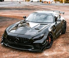 a black sports car parked on top of a dirt field