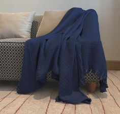 a blue blanket sitting on top of a couch next to pillows