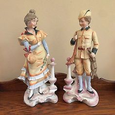 two figurines are standing on top of a wooden table next to each other