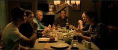 a group of people sitting at a table eating food and drinking wine in a dark room