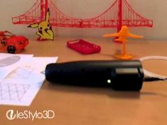 a pen sitting on top of a table next to some paper and toy cars in front of a bridge