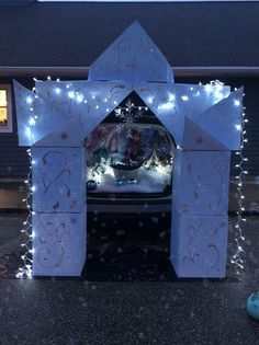 a car is parked in front of a house decorated with lights and snowflakes