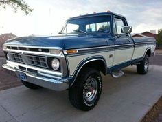 an old blue and white truck parked on the street