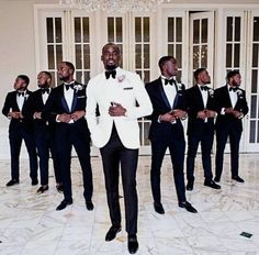 a group of men in tuxedos standing next to each other on a tile floor