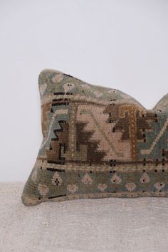 a decorative pillow is sitting on a couch with a white wall in the back ground