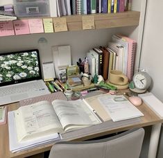 a laptop computer sitting on top of a desk next to a book shelf filled with books