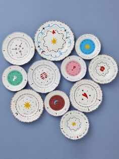 nine plates with designs on them are arranged in the shape of clouds, stars and planets