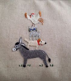 an embroidered pillow with animals and birds on it