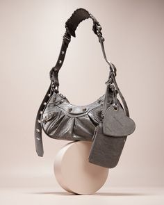 Balenciaga shoulder bag in textured lambskin leather with studded trim  Adjustable shoulder strap, 18,1" drop Zip top closure with tassel pull  Exterior, removable heart charm and zip pouch bag; can be tucked inside  Interior, one main compartment Fabric lining  Approx. 1.1 lbs.  Approx. 6.3"H x 10.2"W x 2.7"D "Cagole" is made in Italy Leather Shoulder Bag Outfit, Balenciaga Shoulder Bag, Shoulder Bag Outfit, First Perfume, Inside Interiors, Studded Leather, Zip Pouch, Pouch Bag, Zip Top