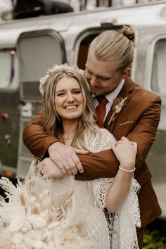 a man and woman hugging each other in front of an old fashioned bus with the door open