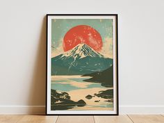 a framed poster on the wall with a mountain and lake in the foreground, under a red sun