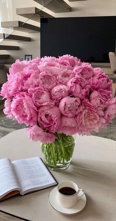 a vase filled with pink flowers sitting on top of a table next to an open book