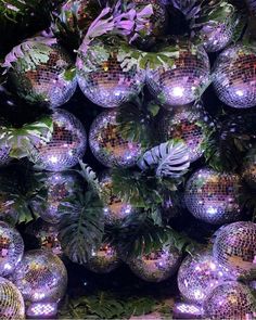 many disco balls are stacked on top of each other in front of plants and foliage