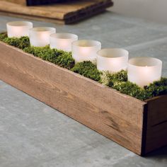 a wooden box with moss and lit candles in it