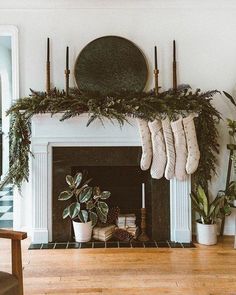 stockings hanging from the mantel above a fireplace with potted plants and candles on it