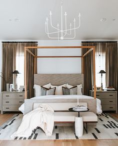 a bedroom with a canopy bed, dressers and lamps on either side of the bed