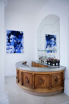 an elegant bar with marble counter tops in a white walled room next to two mirrors