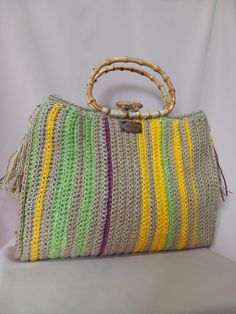 This bag is crocheted entirely by hand. The handle is made of bamboo wood and the internal lining, made of very resistant fabric, has two large pockets. The bag is closed by a wooden button, inserted into a loop. The bag is decorated on the side with two tassels. This is a very roomy, unique and durable bag; It will give a touch of class to your summer clothing. Measures: - Height without handle: 34 cm - Width: 42cm - Depth: 10 cm - Handle height: 14 cm (Please allow 1-2cm size difference since Summer Crochet Jute Bag With Bamboo Handle, Natural Jute Crochet Bag With Bamboo Handle, Natural Color Jute Crochet Bag With Bamboo Handle, Beige Crochet Jute Bag With Bamboo Handle, Beige Jute Crochet Bag With Bamboo Handle, Everyday Crochet Jute Bag With Bamboo Handle, Summer Jute Crochet Bag With Handles, Summer Jute Crochet Bag, Summer Style Crochet Jute Bag With Handles