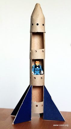 a paper model of a rocket ship with a small figure in the bottom section and an orange toy on top