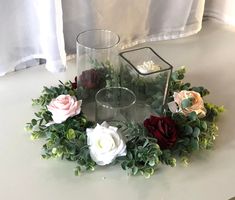 flowers and greenery are arranged in a circle on a table next to a candle holder