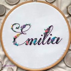 embroidered name art on white fabric surrounded by coins