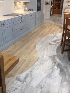 a kitchen with blue cabinets and wood floors is shown in this image, there are wooden chairs around the table