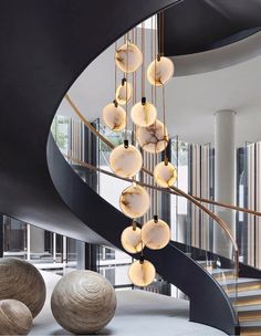 a spiral staircase with glass balls hanging from it's sides in a modern building