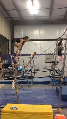 some people are doing tricks on a trampoline in an indoor gym with ropes and ladders