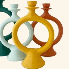 three different colored vases sitting next to each other in front of a white background