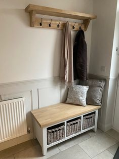 a bench with two baskets underneath it and coat rack on the wall next to it